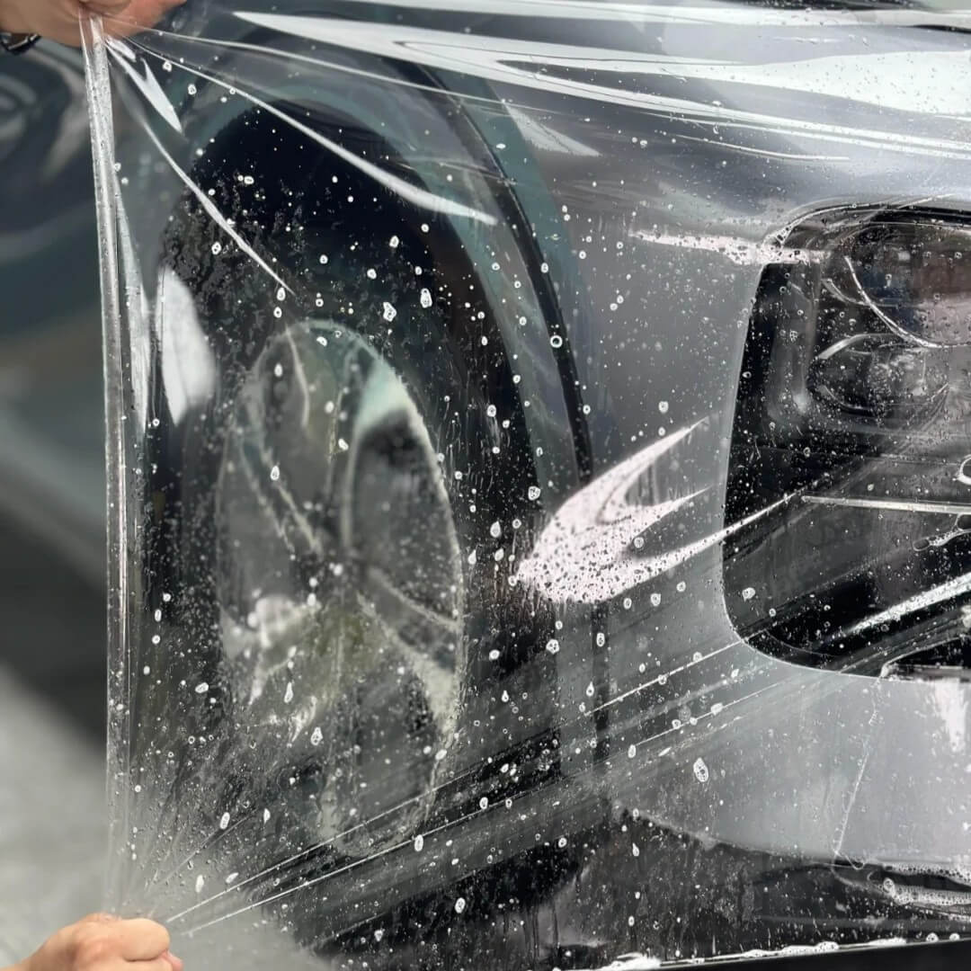 Professional technician installing paint protection film with precision tools